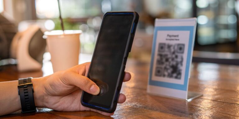Een persoon die met zijn telefoon een QR code scant in een café